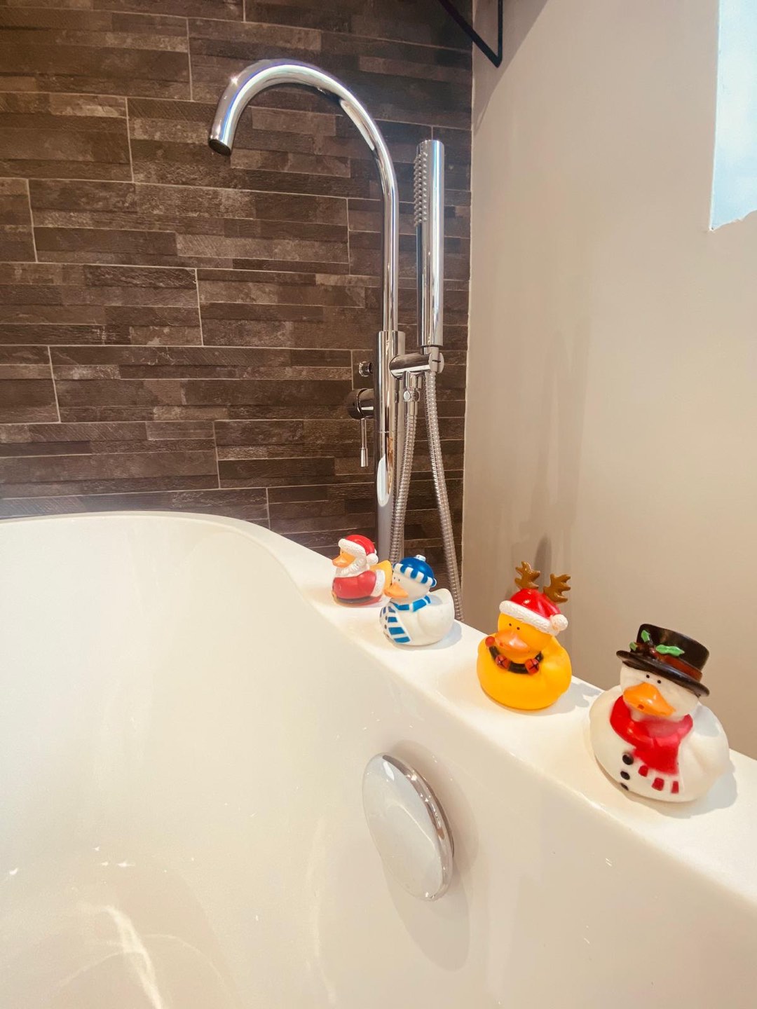 Freestanding bath with chrome floor-standing tap and wood-effect tiled feature wall